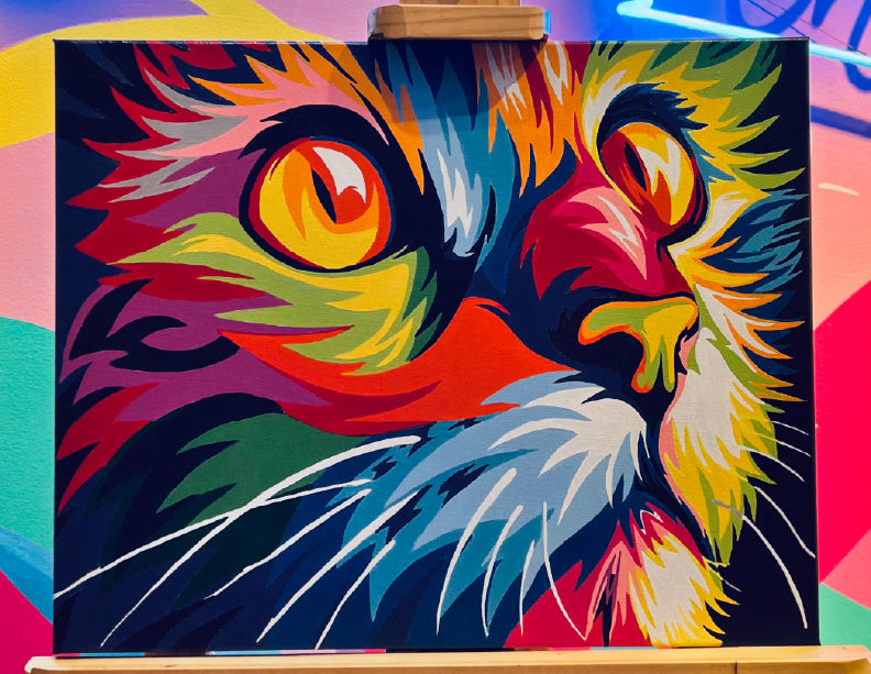 Cuadro de gato colorido con pintura por números en tonos vibrantes de naranja, amarillo, verde y azul.