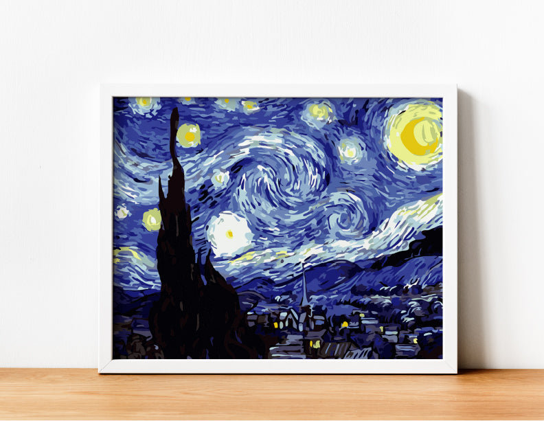 Cuadro de La Noche Estrellada de Van Gogh pintado en estilo por números con marco blanco sobre mesa de madera clara.