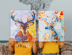 Niños sosteniendo cuadros de renos coloridos para pintar por números, con estilo geométrico y artístico.